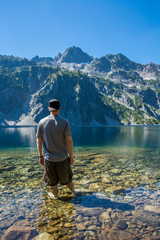 Fototapeta na wymiar Adventurous man standing in an alpine lake.