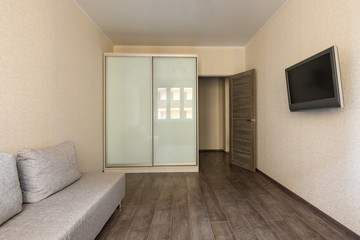 Interior of a small modest room in a hotel, TV, wardrobe and sofa