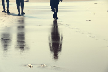 Reflection of two human walking on the beach