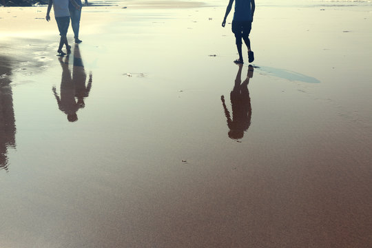Reflection of two human walking on the beach
