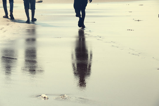 Reflection of two human walking on the beach