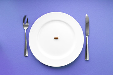A small tablet in a plate. Medical concept. Eat pills instead of food.
