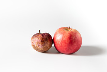 Rotten old and fresh ripe apples on a white background. Trendy ugly food concept. The problem of food waste.