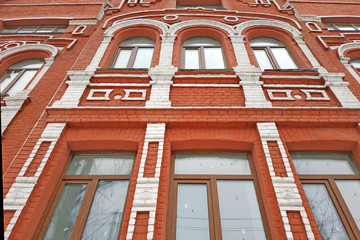 Beautiful red brick building with white trim. Facade of an old house. Wall with windows and arches of an old house bottom view.