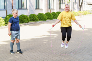 Obraz premium Boy looking at a girl jumping with a rope. Fitness and healthy lifestyle.