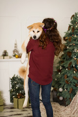 beautiful woman hugs, cuddles with her akita inu dog. on a background of a Christmas tree dresser with candles in a decorated room. happy new year and merry christmas