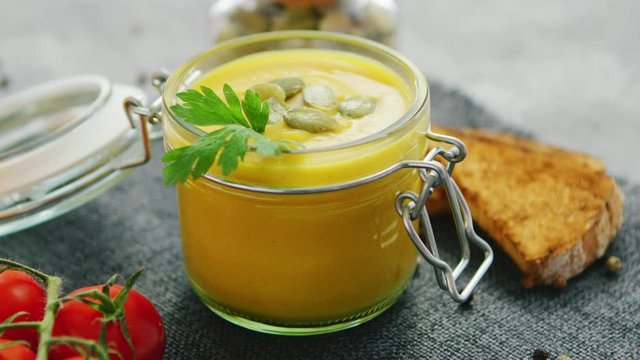 Creamy pumpkin soup in jar with bread and tomatoes