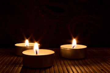 Obraz na płótnie Canvas three candles in the dark, close up