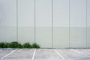 Fototapeta na wymiar Tall concrete wall next to empty parking with copy space