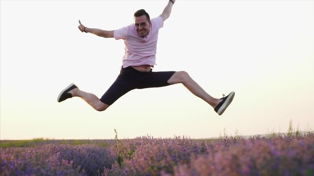 Happy man jumping up in flowering lavender field, slow motion