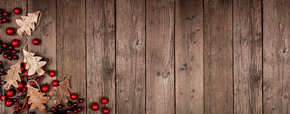 Poster christmas corner border banner with wood tree decorations and red baubles. top view on an rustic woo