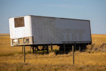 Obraz premium Old abandoned truck trailer parked in a yellow natural grassland prairie or plain rural area. Disuse truck equipment on countryside landscape.