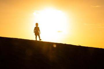 Silueta de Niño en el Atardecer en  el Desierto Frente al sol 