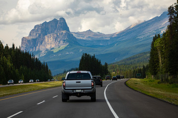 cars, pickups and SUVs are traveling accross the canadian rockies on a 4 lane highway. High...