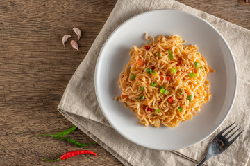 The noodles are in a round white plate placed on a wooden table.copy space