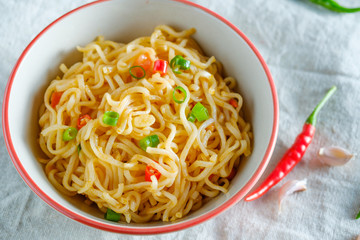 A cup of instant noodles placed on a wooden table With chilli as ingredients ,top view noodle