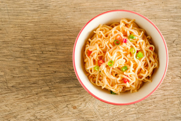 A cup of instant noodles placed on a wooden table With chilli as ingredients ,top view noodle and copy space