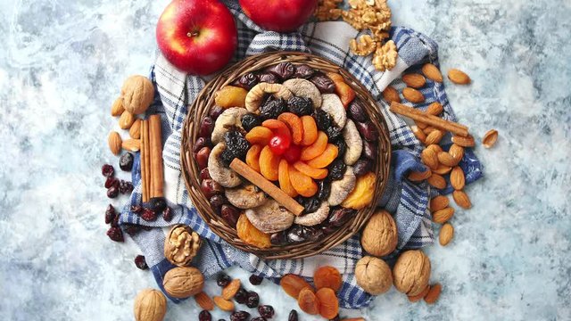 Composition of dried fruits and nuts in small wicker bowl placed on stone table