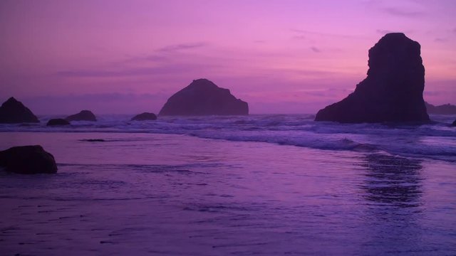 Magical light adds an air of mystery to the purple and pink pastel sky as it drapes over the oceans tide