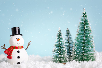 Christmas greeting card. Snowman and new year trees on snow over blue paper background