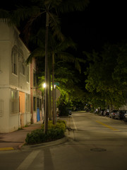 A dark and quiet street illuminated by street lights at night. Miami, Florida, USA