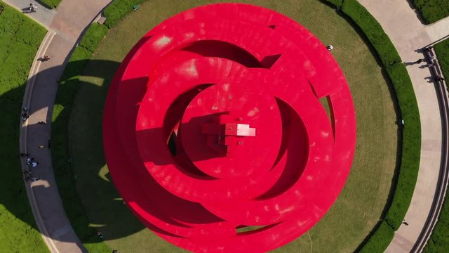Ascending rotating drone shot looking down on artistic red monument on May 4th Square in Qingdao, commemorating the anti imperialist May Fourth Movement of 1919 in China