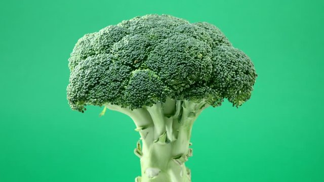 Fresh raw broccoli rotating over green background
