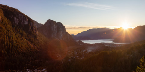 Squamish, North of Vancouver, British Columbia, Canada. Beautiful Aerial Panoramic View from the top of the Mountain of a small town surrounded by Canadian Nature during Autumn Sunset.
