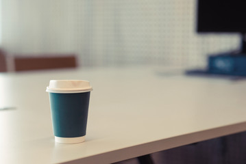 Paper coffee cup on white table in office