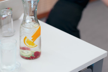 Infused detox water . Fruit infused flavored water, orange slice and kiwi slice in glass jar with glass.