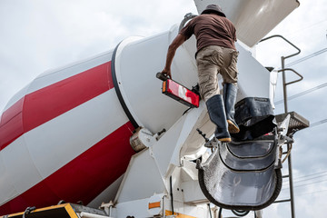 Truck driver washing the cement mixer truck after finish pouring cement. Man standing on the cement...