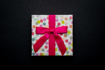Flat lay a single polka dots gift box with ribbon isolated on black background.