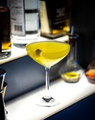 fresh yellow alcohol cocktail with lemon at a restaurant interior, dark background