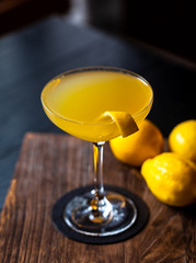 fresh yellow alcohol cocktail with lemon at a restaurant interior, dark background