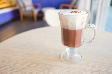 A cup of hot cocoa with whipped cream on table in the cafe