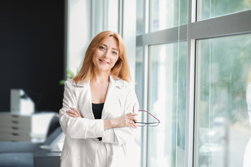 Portrait of mature businesswoman near window in office