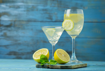 Lemonade or mojito cocktail with lemon and mint on wood background