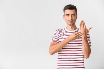 Young deaf mute man using sign language on white background