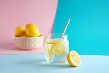 Glass of fresh lemonade on color background