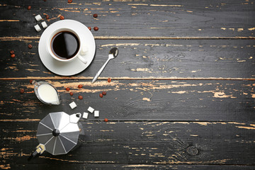 Cup of hot coffee, pot, milk and sugar on dark wooden background