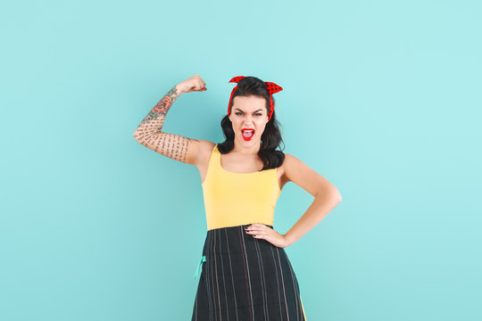 Portrait of strong tattooed pin-up woman on color background