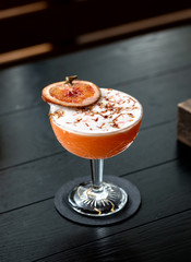 fresh grapefruit with dragon fruit alcohol cocktail at a restaurant interior on dark wooden background