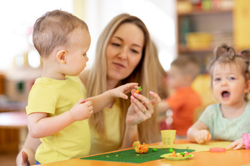 Obraz premium Cute woman and kids with play clay toys at day care center