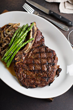 Bone-in ribeye beef steak sliced with mushrooms and asparagus