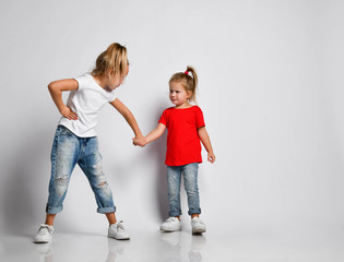 Two kids girls frown at each other, holding hands painfully, trying to endure the pain, not to cry. Family conflict