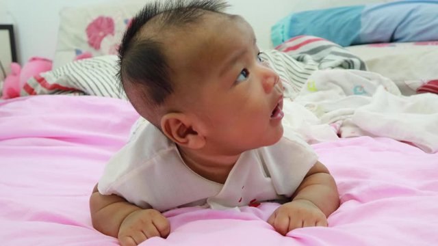Newborn baby lay prone Was playing on the white mattress, refreshing, in a good mood During bedtime, the child's brain will work. To enhance Memory-boosting and learning-building skills