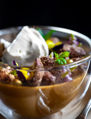 Haute cuisine - dessert with mousse, nuts, chocolate and creme brulee on a wooden plate with spoon and pancakes or crackers on a dark background macro close up
