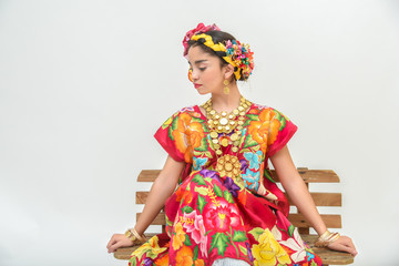 Mexican girl with a floral dress from Oaxaca Mexico, hidden in a red background with braided...