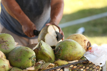 Man chopping green coconut with a machete