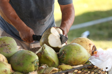 Man chopping green coconut with a machete